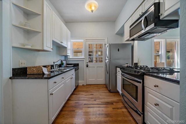 kitchen with sink, appliances with stainless steel finishes, hardwood / wood-style flooring, and white cabinetry