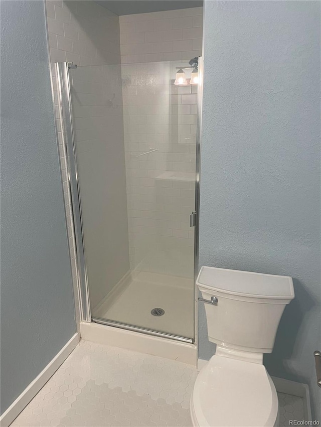 bathroom with a shower with shower door and toilet