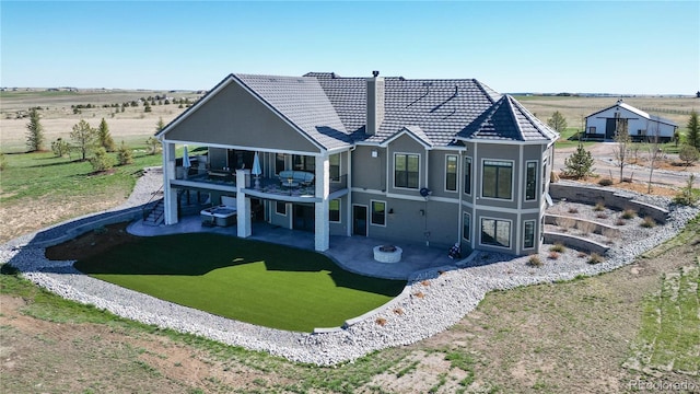 rear view of house with a balcony, a patio area, and a rural view