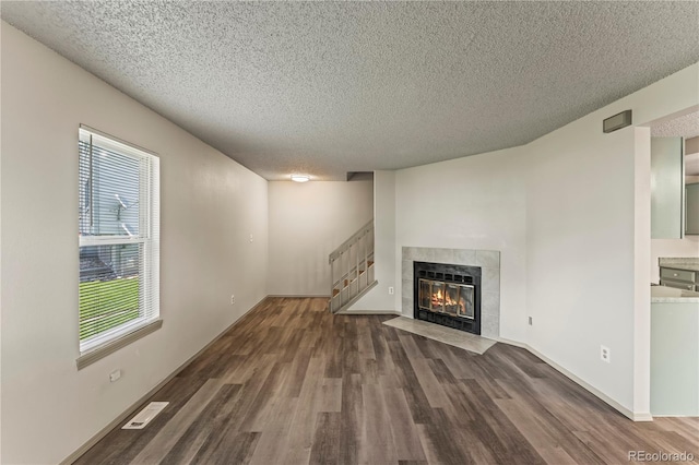 1344 Firefly Cir, Colorado Springs, CO 80916 - unfurnished living room featuring a textured ceiling, wood finished floors, stairs, and a tiled fireplace