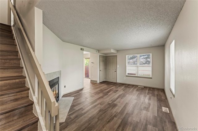 1344 Firefly Cir, Colorado Springs, CO 80916 - unfurnished living room featuring a textured ceiling, wood finished floors, plenty of natural light, and stairs