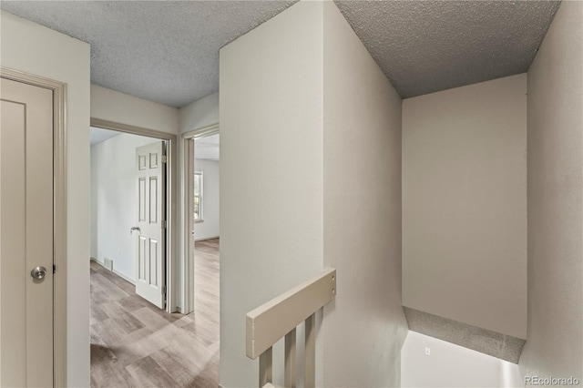 1344 Firefly Cir, Colorado Springs, CO 80916 - corridor with wood finished floors, a textured ceiling, and an upstairs landing