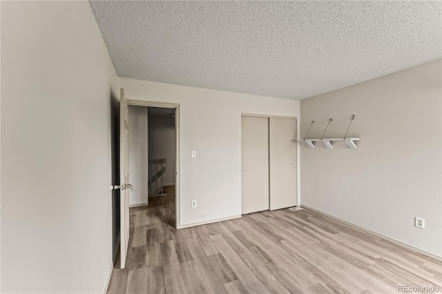 1344 Firefly Cir, Colorado Springs, CO 80916 - unfurnished bedroom with light wood-style floors, a closet, and a textured ceiling
