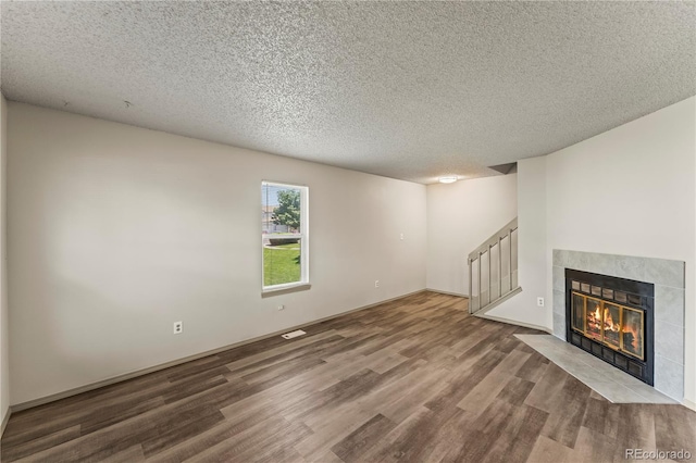 1344 Firefly Cir, Colorado Springs, CO 80916 - unfurnished living room with wood finished floors, stairway, a textured ceiling, and a tile fireplace