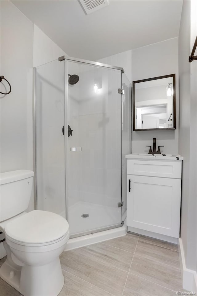 bathroom with vanity, toilet, and a shower with shower door