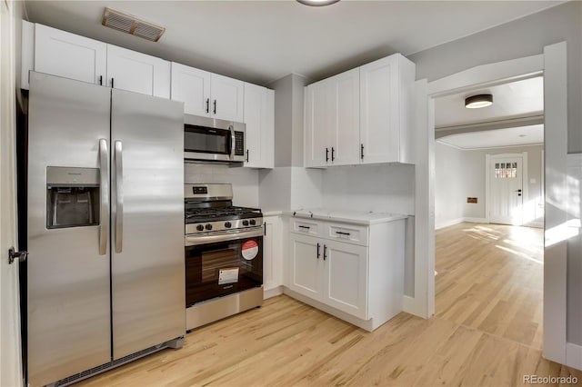 2103 S Lafayette St, Denver, CO 80210 - kitchen with appliances with stainless steel finishes, white cabinets, light wood-style flooring, and light stone countertops