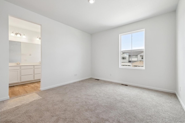 6636 N Nepal St, Aurora, CO 80019 - unfurnished bedroom featuring light colored carpet, baseboards, a sink, and ensuite bathroom