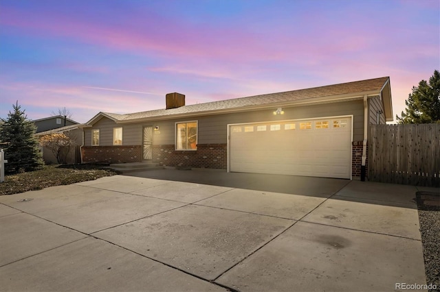 ranch-style home featuring brick siding, concrete driveway, an attached garage, and fence