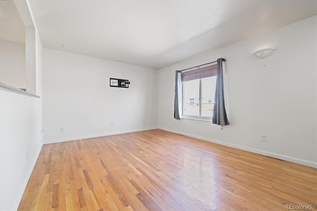 unfurnished room with light wood-style flooring and baseboards