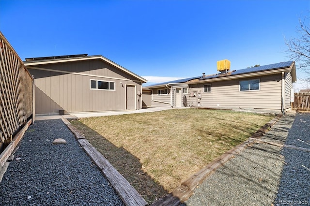 back of property featuring a patio area, roof mounted solar panels, a lawn, and a fenced backyard