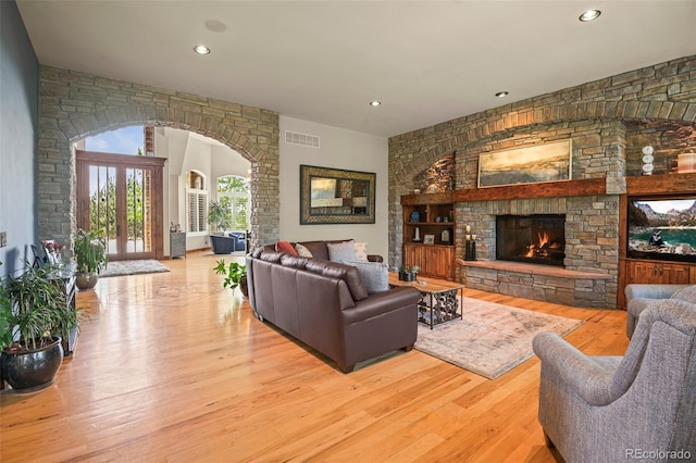 living room featuring french doors, a stone fireplace, and light wood-type flooring