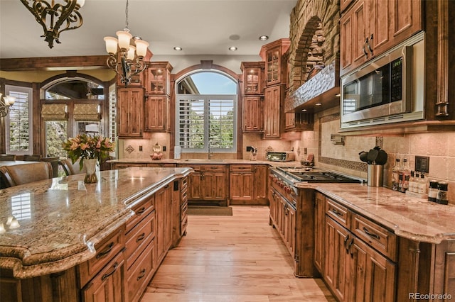 kitchen featuring appliances with stainless steel finishes, a notable chandelier, a kitchen breakfast bar, and decorative light fixtures