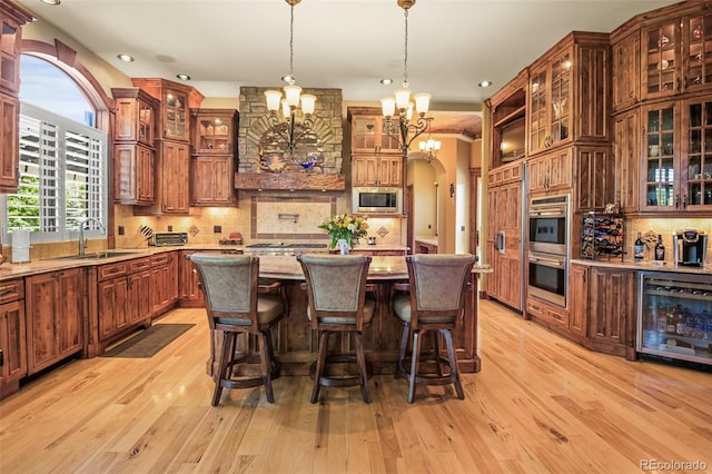 kitchen with pendant lighting, sink, appliances with stainless steel finishes, wine cooler, and light stone countertops