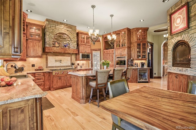 kitchen featuring sink, light stone counters, hanging light fixtures, appliances with stainless steel finishes, and a kitchen island