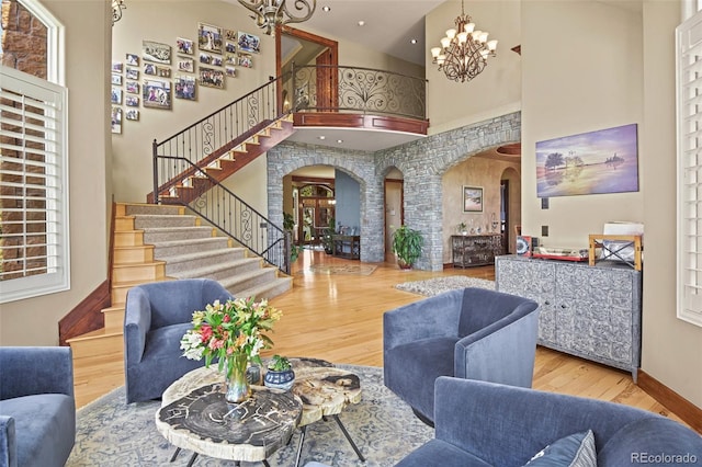 living room featuring a notable chandelier, a towering ceiling, and hardwood / wood-style floors