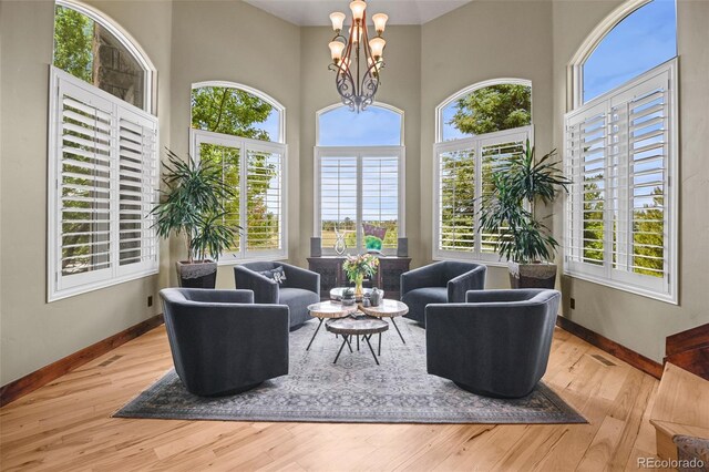 living room featuring a notable chandelier, light hardwood / wood-style flooring, and a high ceiling