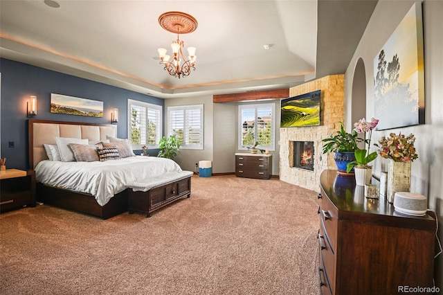 bedroom featuring a raised ceiling, carpet, a chandelier, and a fireplace