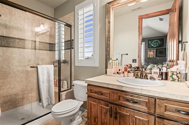 bathroom featuring toilet, vanity, and a shower with shower door