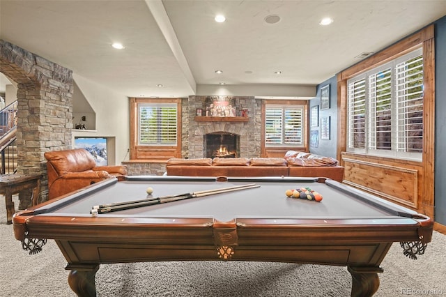 game room featuring a stone fireplace and light colored carpet