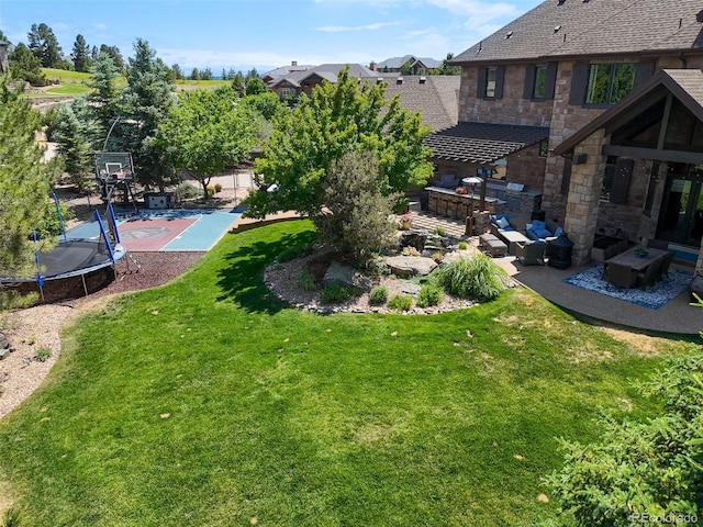 view of yard featuring a trampoline and basketball court