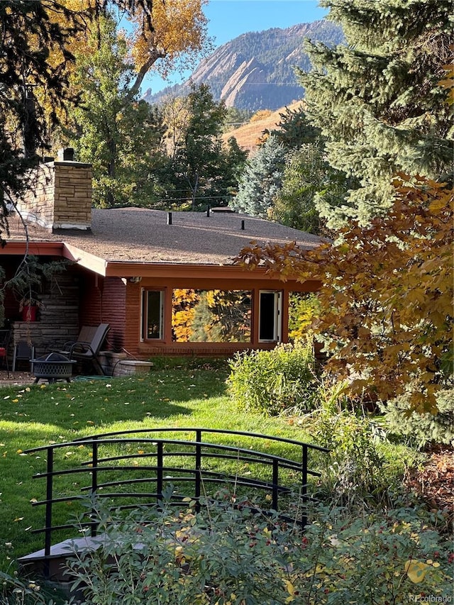 rear view of property featuring a yard, a chimney, and a mountain view