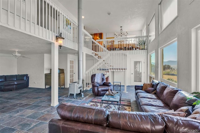 living room with a textured ceiling, ceiling fan with notable chandelier, and a high ceiling