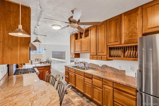 kitchen featuring light stone counters, pendant lighting, sink, a textured ceiling, and stainless steel appliances