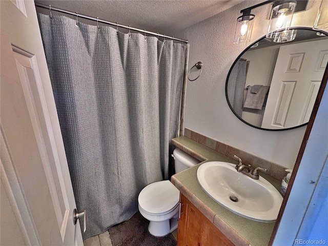 bathroom featuring a shower with curtain, vanity, toilet, and a textured ceiling