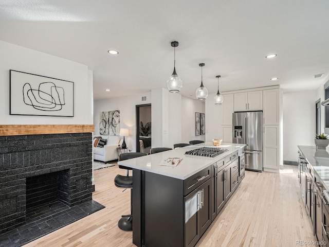 kitchen with a kitchen island, a breakfast bar area, decorative light fixtures, light countertops, and high end fridge