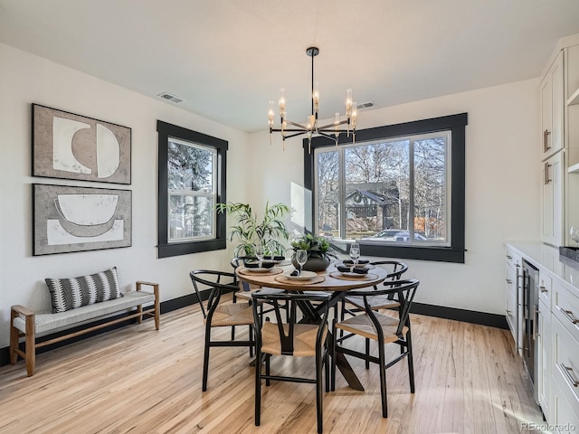 dining space with a chandelier, light wood-type flooring, visible vents, and baseboards