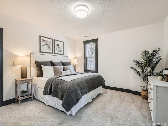 bedroom featuring baseboards, a textured ceiling, and light colored carpet