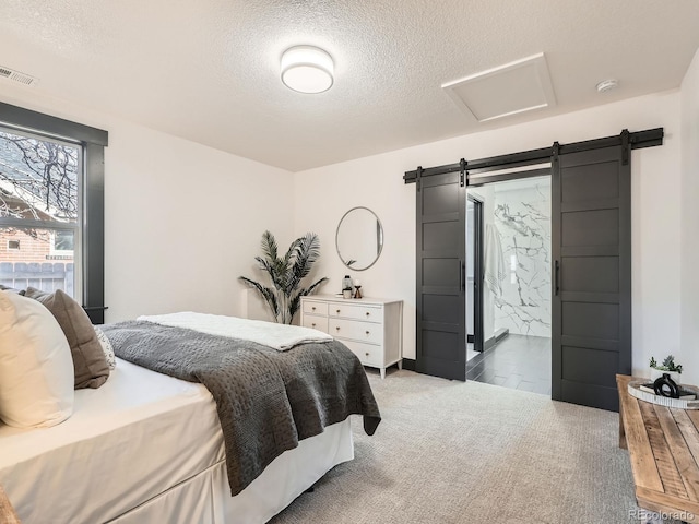 carpeted bedroom with attic access, visible vents, a textured ceiling, and a barn door