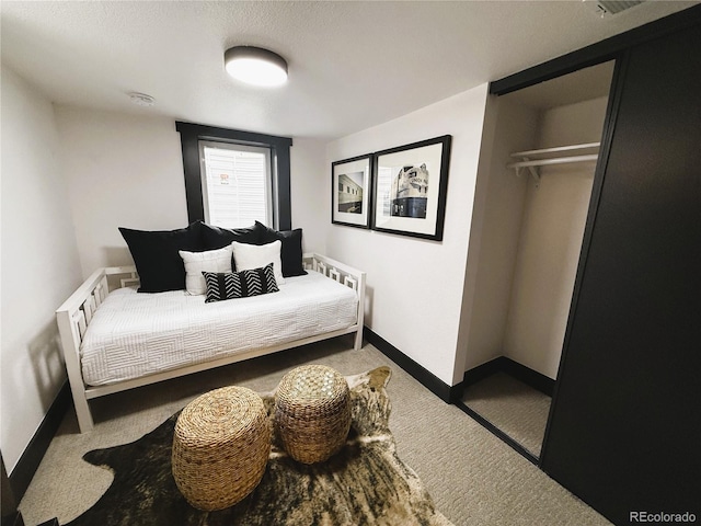 carpeted bedroom with a closet and baseboards