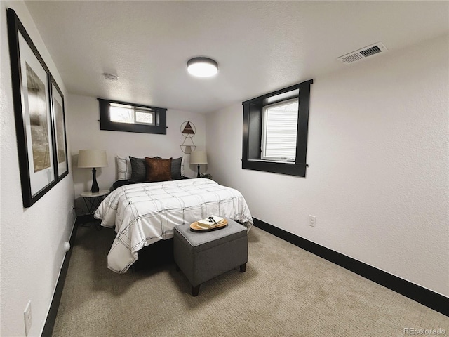 bedroom with a textured ceiling, carpet floors, visible vents, and baseboards