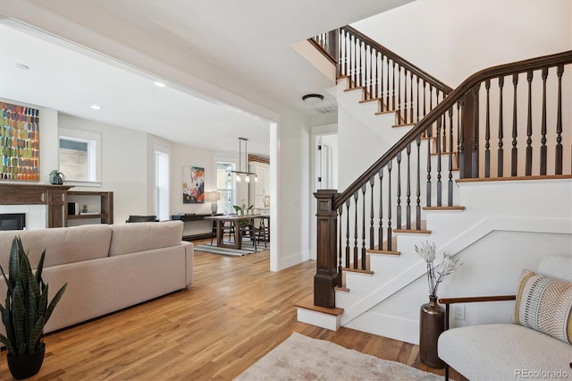 interior space featuring baseboards, stairway, wood finished floors, and a glass covered fireplace