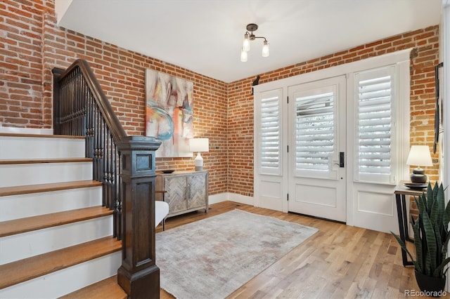 foyer featuring stairs, brick wall, and wood finished floors