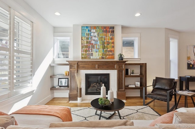 living room featuring baseboards, a tiled fireplace, wood finished floors, and recessed lighting