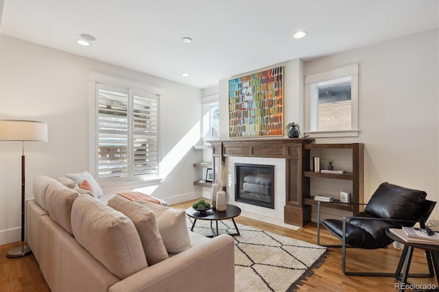 living room with recessed lighting, baseboards, wood finished floors, and a tile fireplace