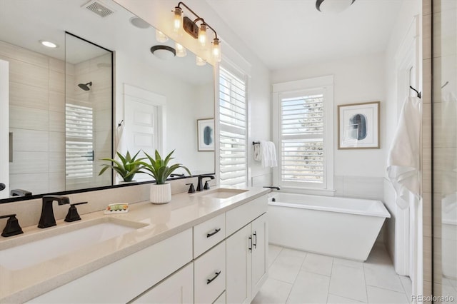 bathroom with a freestanding tub, visible vents, a sink, and tile patterned floors