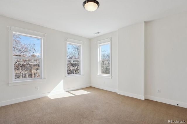 spare room with visible vents, baseboards, and carpet flooring