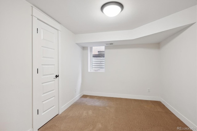 below grade area with light carpet, visible vents, and baseboards