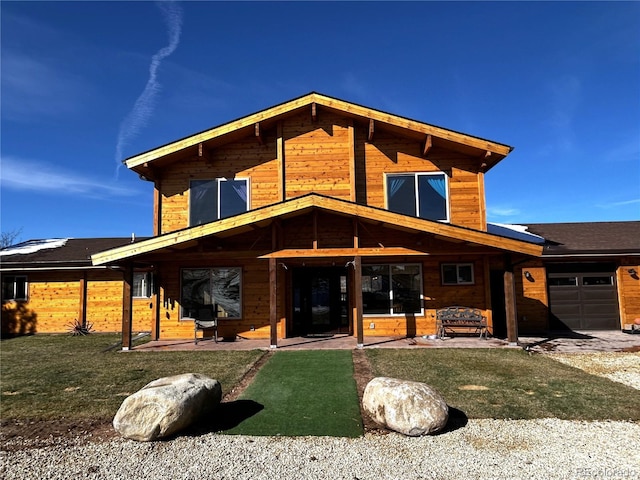 rear view of property featuring a lawn and a garage