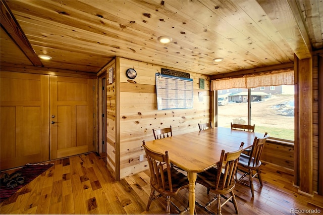 dining area with wood walls, wood ceiling, and light hardwood / wood-style flooring