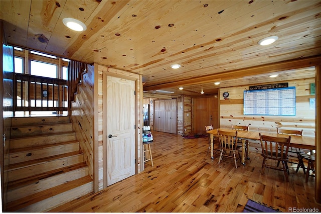 dining area with light hardwood / wood-style floors, wooden ceiling, and wood walls