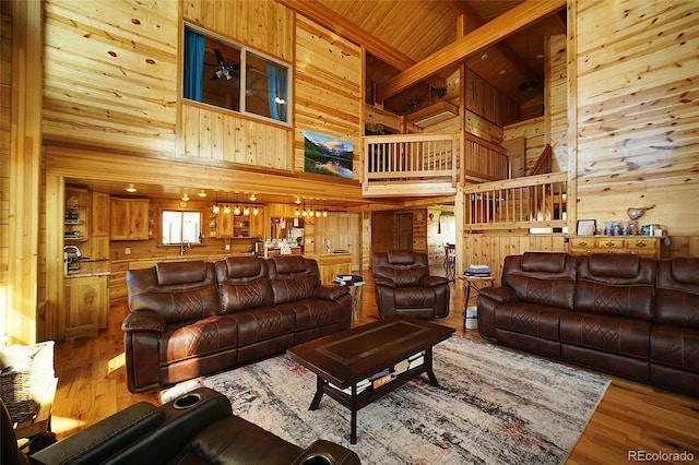 living room with beamed ceiling, hardwood / wood-style flooring, high vaulted ceiling, and wooden walls