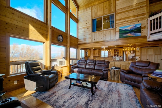 living room with wood walls, wood-type flooring, and a high ceiling