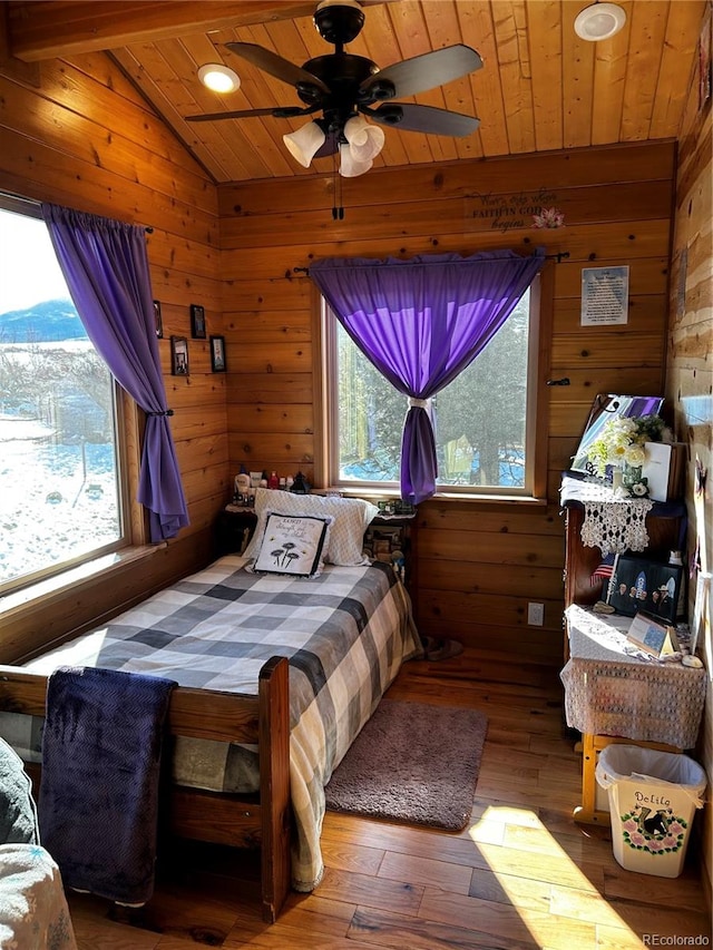 bedroom featuring hardwood / wood-style flooring, ceiling fan, wood walls, and lofted ceiling