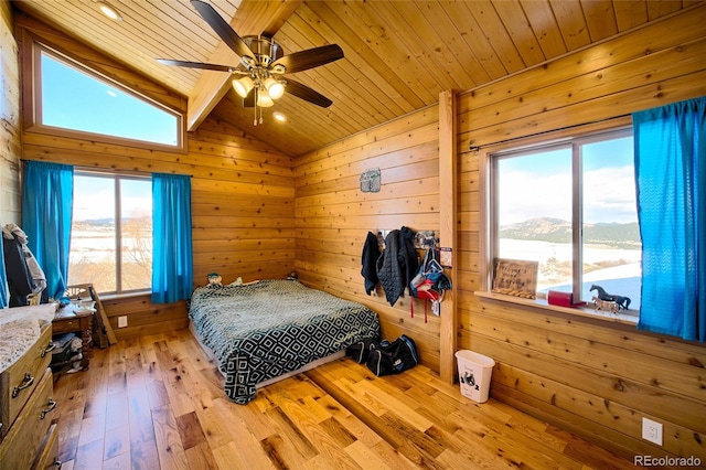 bedroom with wood walls, lofted ceiling, wooden ceiling, ceiling fan, and light wood-type flooring