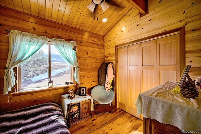 bedroom featuring vaulted ceiling with beams, light hardwood / wood-style flooring, wood ceiling, and wood walls