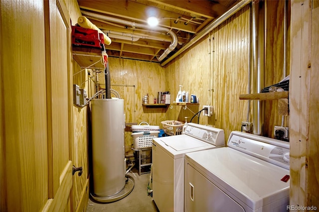 clothes washing area featuring wood walls, separate washer and dryer, and water heater